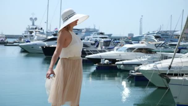 Woman in hat and sunglasses on the background makes selfie bay with yachts. Girl in a skirt-the sun is spinning and rejoicing. 4k slow motion. — Stock Video