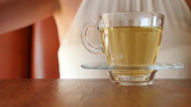 Kız şeffaf bir kupa yeşil çay ile kahverengi şeker bir parça koyar. Hava kabarcıkları yükselin. 4k, ağır çekim.