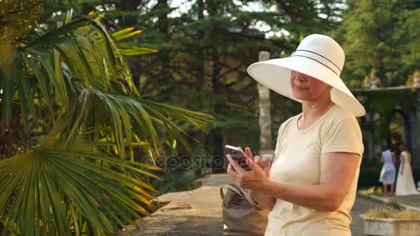 美丽的老年妇女或旅游与移动手机智能手机拍照。夫人，分享 pic 社交媒体照片网站上。4 k.慢动作 — 图库视频影像