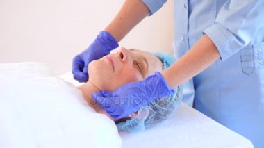 Yaşlı kadın yüz maskesi alma için Spa terapi. 4 k. ağır çekim. Bir güzellik uzmanı alımı