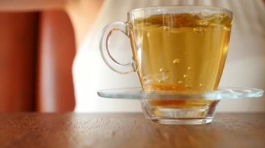 Kız şeffaf bir kupa yeşil çay ile kahverengi şeker bir parça koyar. Hava kabarcıkları yükselin. ağır çekim.