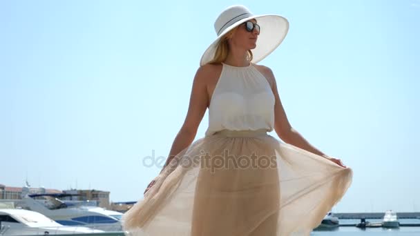 Mulher de chapéu e óculos de sol no fundo faz baía selfie com iates. Menina em uma saia-o sol está girando e se alegrando. 4k câmera lenta . — Vídeo de Stock
