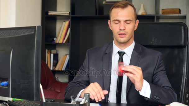 Spinner rojo de la mano, o spinner inquieto, girando en la mano de los hombres. Un hombre con traje haciendo girar a un hilandero nervioso en su oficina en su escritorio. Torceduras en la nariz. 4k. Movimiento lento — Vídeos de Stock