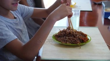 Çocuk buğday noodle çubuklarla yiyor. 4 k. ağır çekim çekim.