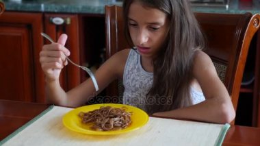 Küçük kız, isteksizce bir çatalla buğday noodle yemek yer. Çocuk yemek reddediyor. 4. Ağır çekim çekim.