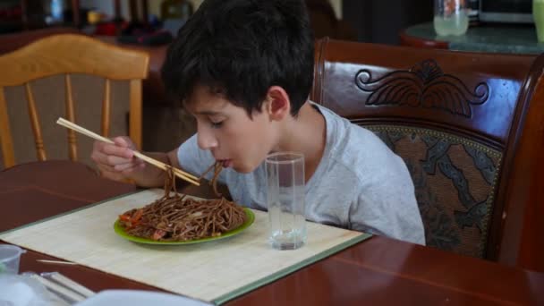Chłopiec zjada makaron gryczany z pałeczkami. 4 k. Slow-motion fotografowania. — Wideo stockowe