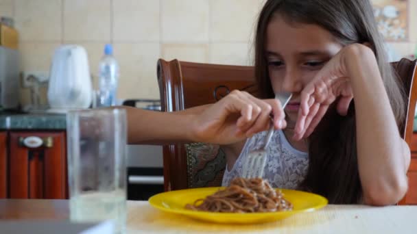 La niña come fideos de trigo sarraceno con un tenedor a regañadientes. El niño se niega a comer. 4. Disparos en cámara lenta . — Vídeo de stock