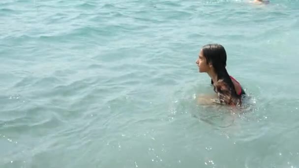 一位少女洒进海浪在海滩上。她追浪，非常高兴。4 k.慢动作 — 图库视频影像
