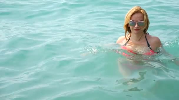 Una giovane donna con un seno grande esce dal mare. Bellissimi seni di giovani in bikini sulla spiaggia. Il viaggio, il concetto di estate. 4k, rallentatore . — Video Stock