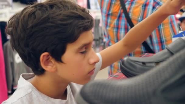 Подросток смотрит на одежду в модном магазине. 4k slow motion — стоковое видео