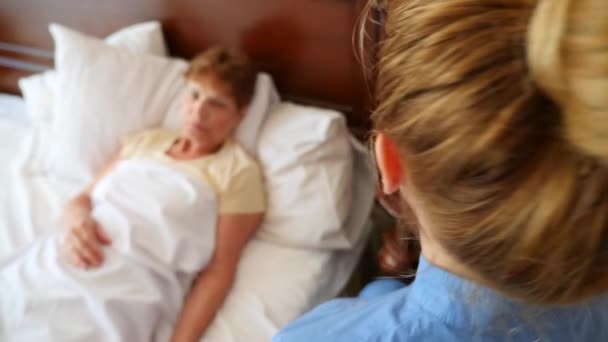 Een verpleegkundige helpt een patiënt in zijn slaapkamer. 4k, slow-motion — Stockvideo