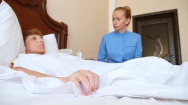 Bir hemşire yatak odasında bir hastada yardımcı olur. 4k, ağır çekim