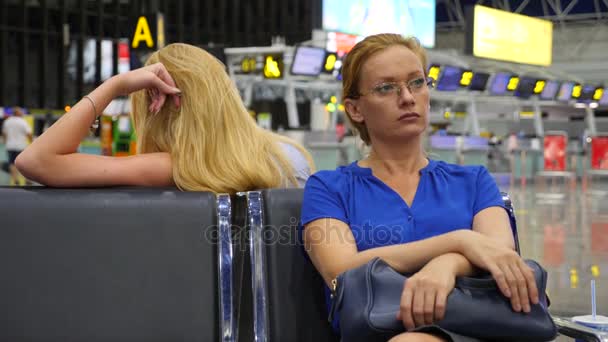 Frau in der Wartehalle des Flughafens. Flugerwartungen am Flughafen. 4k, Zeitlupe, das Mädchen am Flughafen blickt auf die Informationstafel. — Stockvideo