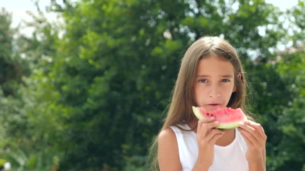 Piękna mała brunetka dziewczyna z długimi włosami jedzenie arbuza poza. 4 k. zwolnionym tempie. — Wideo stockowe