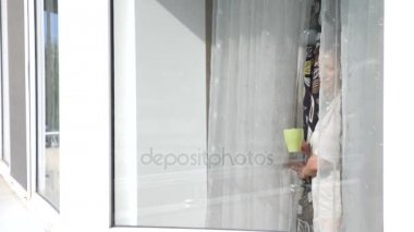 Çekici bir genç kadın ağır çekimde perdeleri açar, onun evinde penceresinin beklemedeyiz gündoğumu, bakar. Bir fincan çay veya kahve. 4 k. ağır çekim.