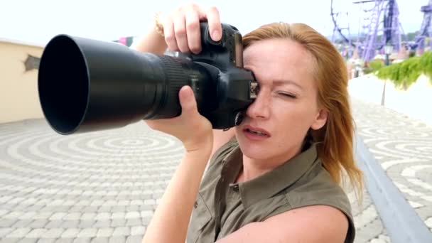 Um close-up de uma fotógrafa está tirando fotos na rua com a ajuda de uma câmera profissional. 4k, câmera lenta — Vídeo de Stock