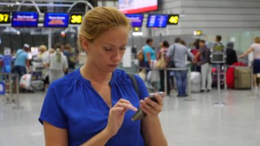 Kadın bir smartphone Havaalanı lounge bekleyen kullanır. Havaalanında uçuş beklentilerini. 4k, ağır çekim