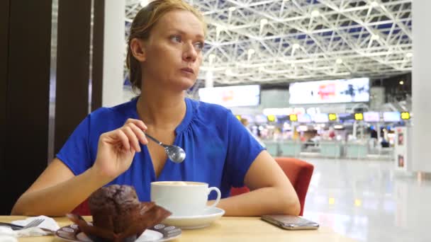 Γυναίκα χρησιμοποιεί ένα smartphone στο αεροδρόμιο σε αναμονή lounge. Πίνει καφέ. Προσδοκίες της πτήσης στο αεροδρόμιο. 4k, αργή κίνηση — Αρχείο Βίντεο
