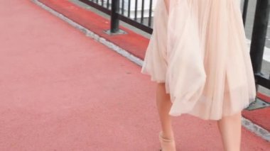 Bir şapka ve beyaz hava elbise zarif bir kadında Rıhtımlar elini kolunu sallaya dönüyor. Bacaklar yakın çekim. 4k, ağır çekim