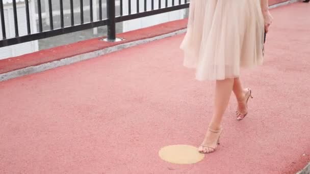 Une femme élégante coiffée d'un chapeau et d'une robe blanche se promène le long du front de mer. Jambes rapprochées. 4k, au ralenti — Video