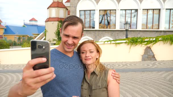 Feliz pareja de turistas fotografiando una selfie en una calle de la ciudad en un día soleado. 4k, cámara lenta . — Vídeos de Stock