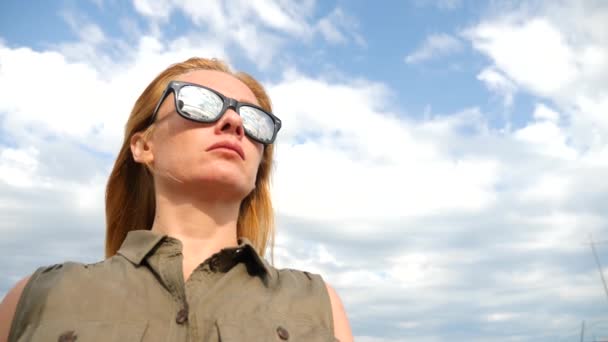 Nahaufnahme Porträt einer Frau, die im Wind gegen den Himmel mit Wolken steht. Haare entwickeln sich im Wind, 4k, Zeitlupe — Stockvideo