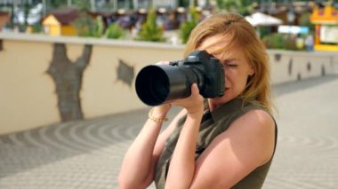 Bir kadın fotoğrafçı bir close-up profesyonel bir kamera yardımı ile sokakta fotoğraf çekmek. 4k, ağır çekim