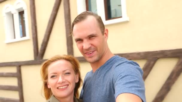Casal feliz de turistas fotografando uma selfie em uma rua da cidade em um dia ensolarado. 4k, câmera lenta . — Vídeo de Stock