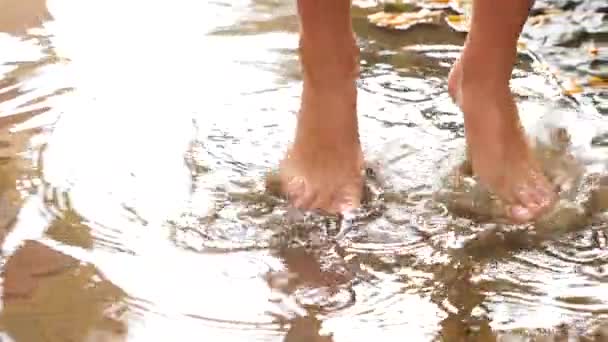 Les pieds nus éclaboussent dans les flaques d'eau regroupées sur des pavés rouges pendant un orage, ralentit le mouvement. 4k — Video