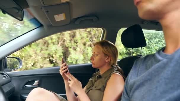 Een vrouw is het rijden in de auto naast de chauffeur en is praten over de telefoon. 4k, slow-motion — Stockvideo