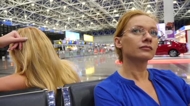 Donna in sala d'attesa all'aeroporto. Aspettative di volo in aeroporto. 4k, rallentatore, la ragazza all'aeroporto guarda il tabellone informativo . — Video Stock