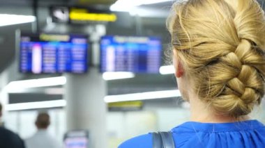 Kadın Havaalanı bekleme salonunda. Havaalanında uçuş beklentilerini. 4k, ağır çekim, bilgi yönetim kurulu Havaalanı bakar kıza.