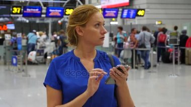 Kadın bir smartphone Havaalanı lounge bekleyen kullanır. Havaalanında uçuş beklentilerini. 4k, ağır çekim