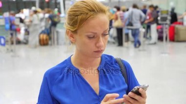 Kadın bir smartphone Havaalanı lounge bekleyen kullanır. Havaalanında uçuş beklentilerini. 4k, ağır çekim