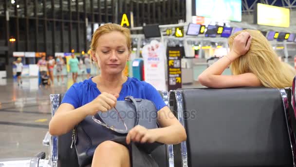 Mujer en la sala de espera del aeropuerto. Expectativas de vuelo en el aeropuerto. 4k, cámara lenta, la chica en el aeropuerto mira el tablero de información . — Vídeos de Stock