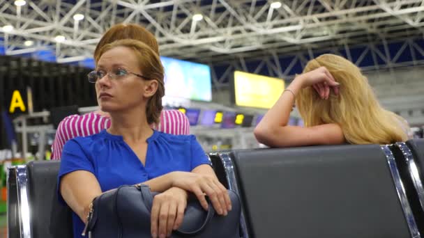 Donna in sala d'attesa all'aeroporto. Aspettative di volo in aeroporto. 4k, rallentatore, la ragazza all'aeroporto guarda il tabellone informativo . — Video Stock