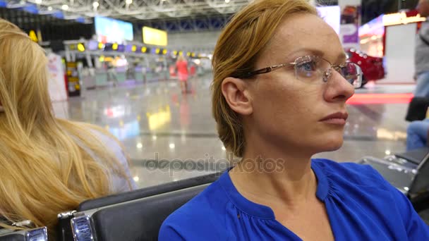 Vrouw in luchthaven wachten lounge. Verwachtingen van de vlucht op de luchthaven. 4k, Slowmotion, het meisje op de luchthaven kijkt het informatiebord. — Stockvideo