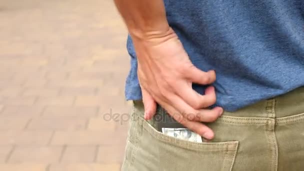 Кто-то теряет 100 долларов из карманов, которые падают на тротуар в городе. 4k, slow motion — стоковое видео