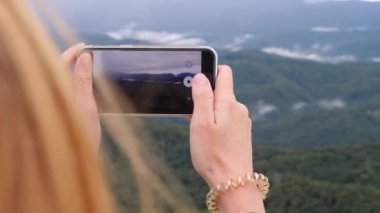 Yavaş çekimde bir selfie alarak dağın tepesine genç kadın. Genç uzun yürüyüşe çıkan kimse kadın alarak dağın zirvesine dağlardan telefonunuza bir görünümünü fotoğraflar. 4k