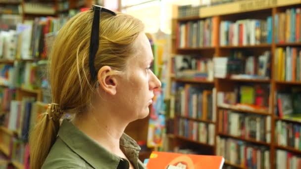 Portret van een vrouw in de bibliotheek. Boekenkast-boekenkasten op achtergrond. 4k, slow-motion — Stockvideo