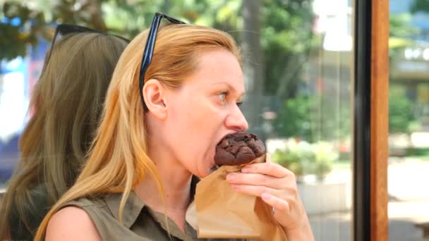 Een dikke vrouw eet een cupcake in een café en SIP's omlaag koffie, 4k, slow-motion — Stockvideo