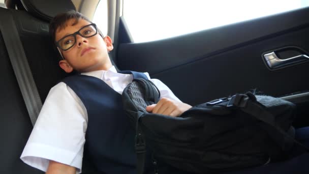 El chico triste va en el coche con el uniforme escolar. 4k, cámara lenta — Vídeo de stock