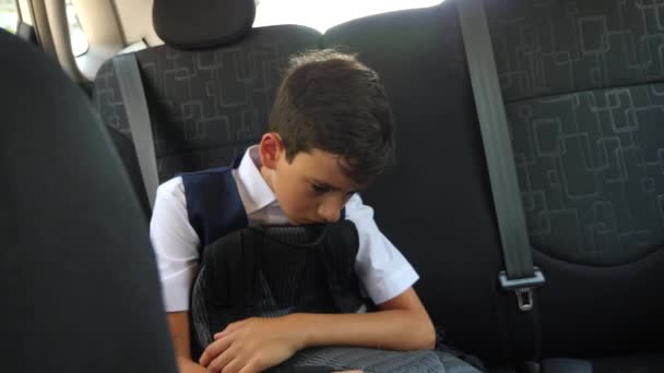 Грустный мальчик едет в машине в школьной форме. 4k, slow-motion — стоковое видео