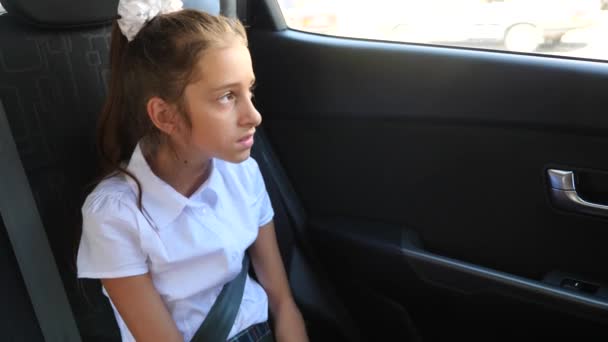 Девочка, скучающая в машине - глядя в окно через окно - уличное отражение, 4к, замедленная съемка — стоковое видео