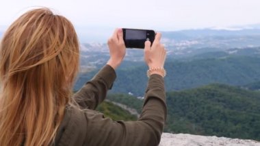 Yavaş çekimde bir selfie alarak dağın tepesine genç kadın. Genç uzun yürüyüşe çıkan kimse kadın alarak dağın zirvesine dağlardan telefonunuza bir görünümünü fotoğraflar. 4k