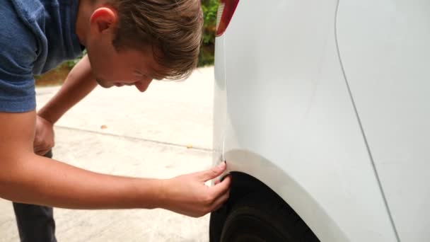 Regardant un véhicule endommagé. l'homme inspecte les dommages à la voiture après un accident. 4k, au ralenti — Video