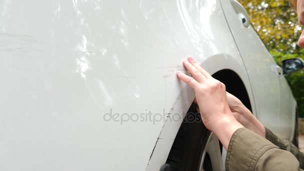 Regardant un véhicule endommagé. Femme blonde inspecte les dommages à la voiture après un accident. 4k, au ralenti — Video