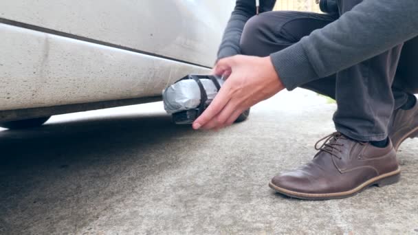 A man puts a homemade explosive device under the car. Preparation of terrorist act. 4k. Slow motion — Stock Video