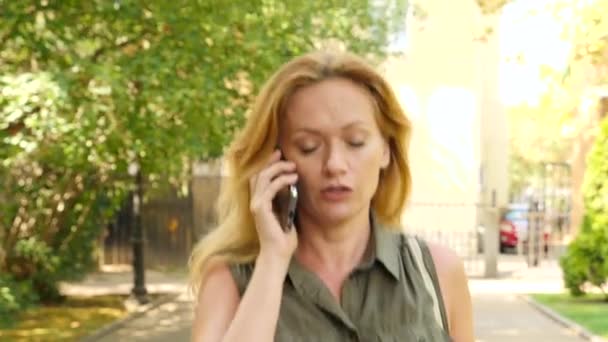 Jonge vrouw is praten over de telefoon op de vlucht, ze is in een haast. 4k, slow-motion — Stockvideo