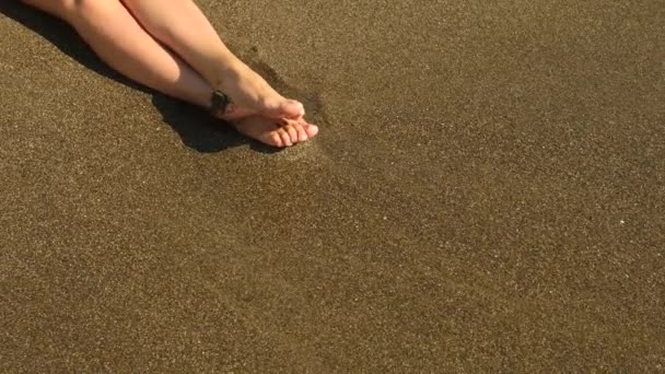 慢动作特写： 年轻女性，长长的腿，走在海滩上和大海水喷洒到照相机。4 k — 图库视频影像
